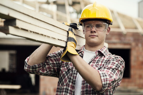 Young construction worker carrying wood boards